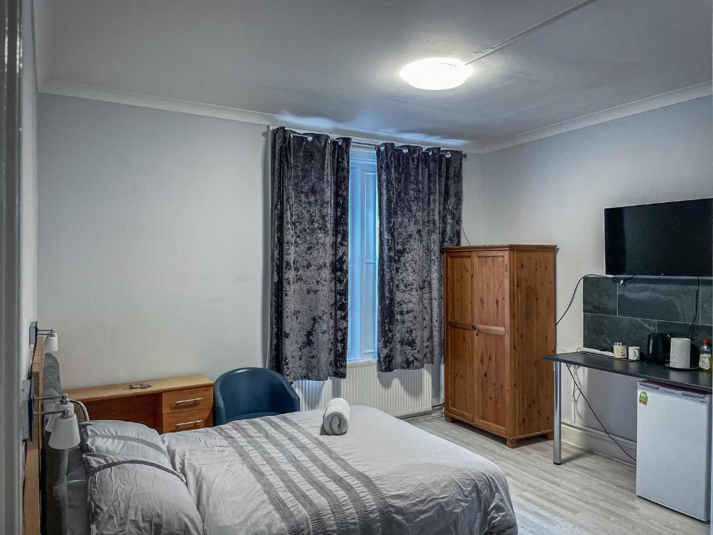 ニューカッスル・アポン・タインにあるThe New George Hotelのベッドとテレビが備わるホテルルームです。