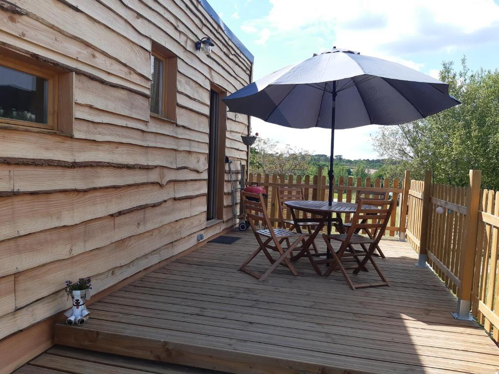 a wooden deck with a table and an umbrella at tiny house in Saint-Vallier