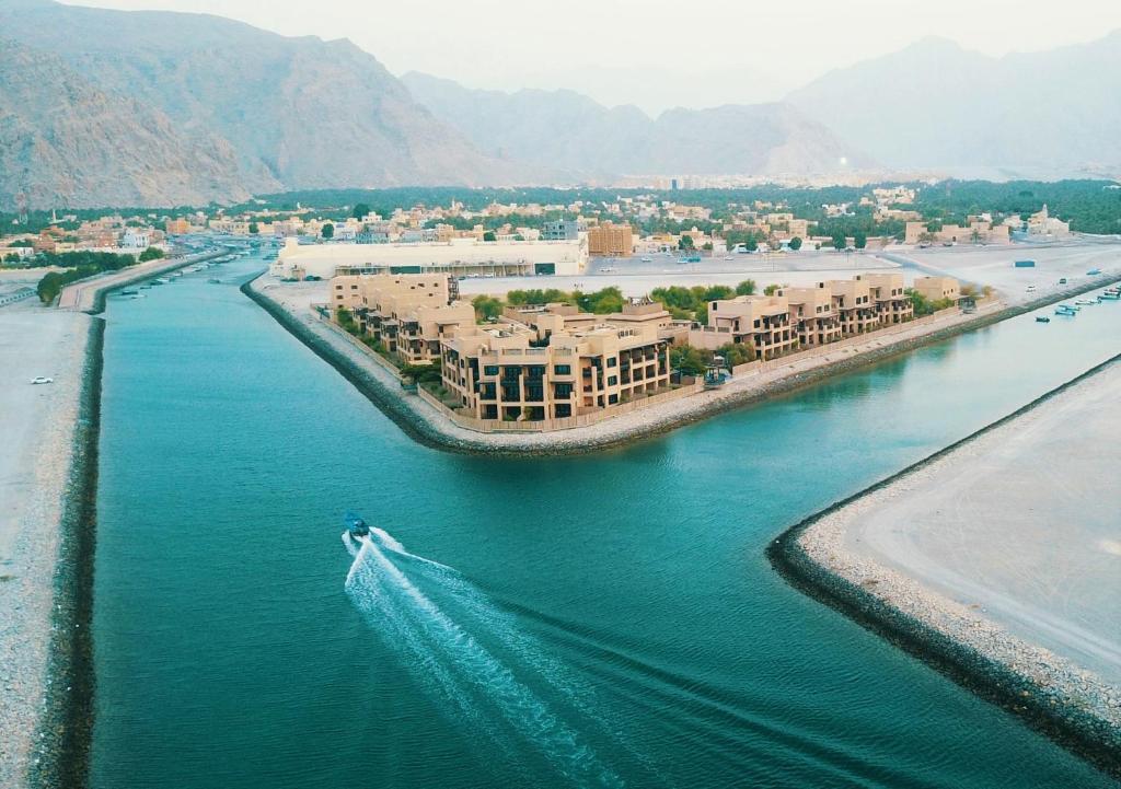 a boat in the water on a river with buildings at Atana Musandam Resort in Khasab