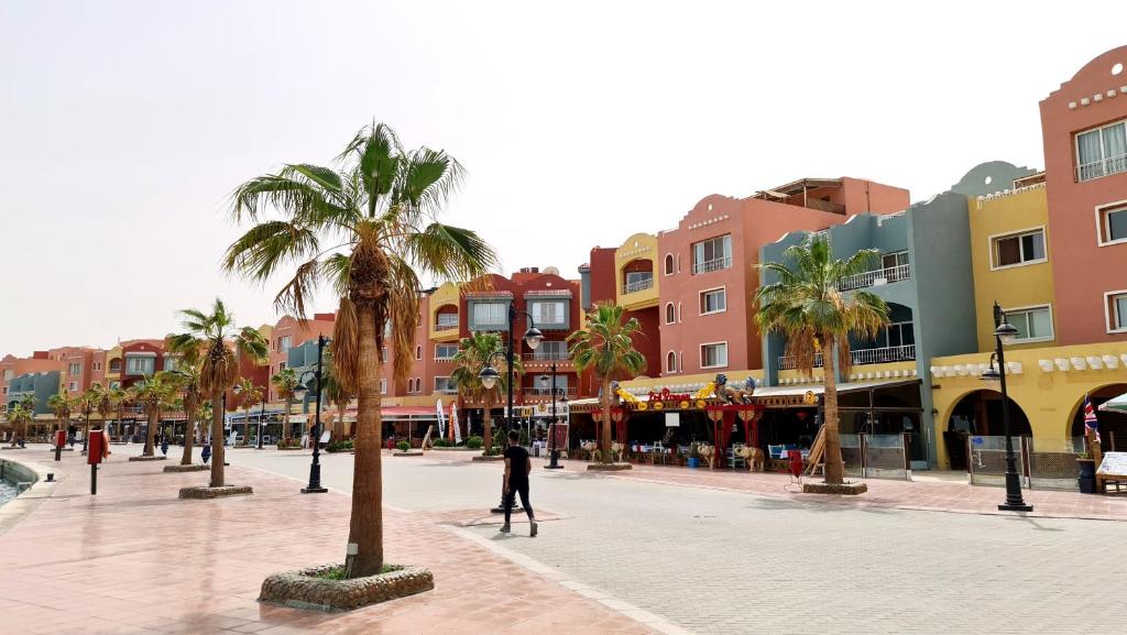 a person walking down a street with palm trees at Rare New Marina Hotspot With Pool & Fast Free WIFI - Western Standards - Sheraton Plaza 415 in Hurghada