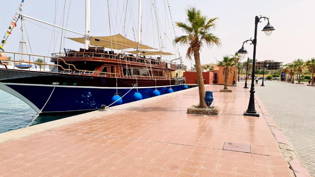 a large boat parked next to a sidewalk with a palm tree at Rare New Marina Hotspot With Pool & Fast Free WIFI - Western Standards - Sheraton Plaza 415 in Hurghada