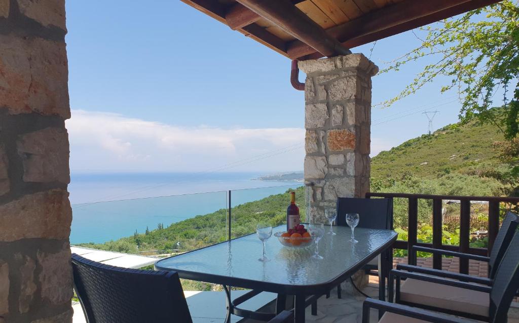 a table with wine glasses on a balcony with a view at Nireas : Stone Villa in Zakynthos