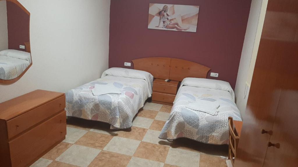 Habitación pequeña con 2 camas y espejo. en Hostal Los Amigos, en La Roda