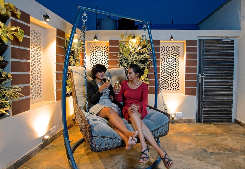 dos mujeres sentadas en una silla mecedora mirando un celular en Blue Beds Hostel, en Jaipur