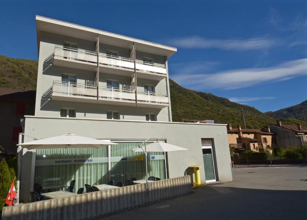 a white building with tables and umbrellas in front of it at Albergo Elvezia in Rivera