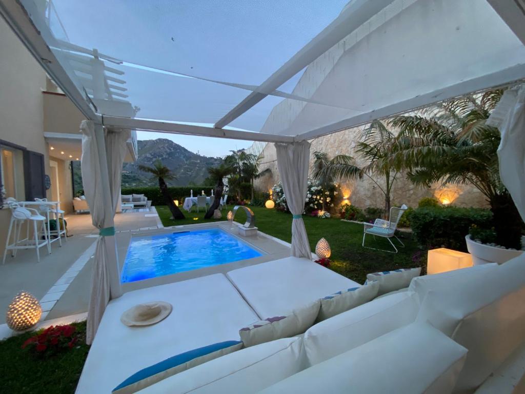 a backyard with a swimming pool and a white pergola at Villa Mastrissa Taormina in Taormina