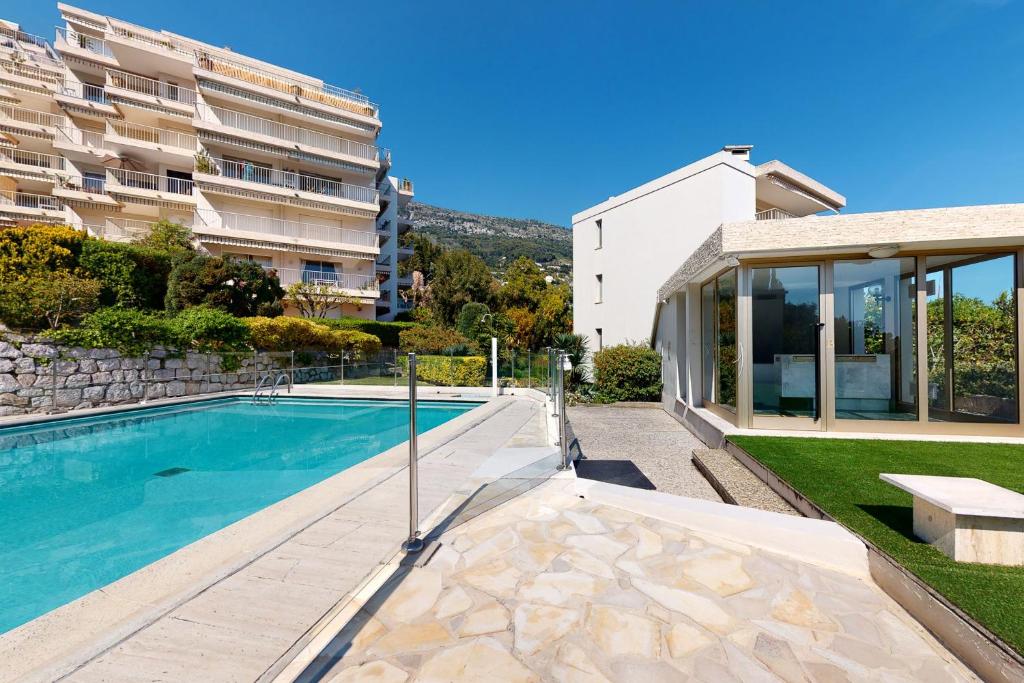 a house with a swimming pool next to a building at Studio les palmiers in Menton