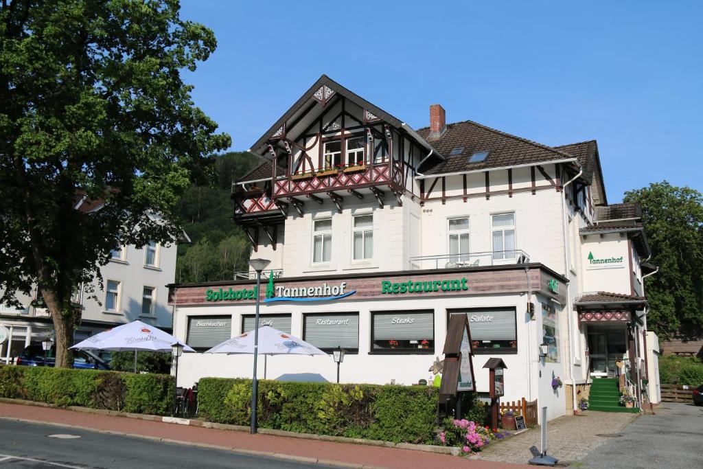 ein weißes Gebäude mit Sonnenschirmen davor in der Unterkunft Hotel Tannenhof in Bad Harzburg