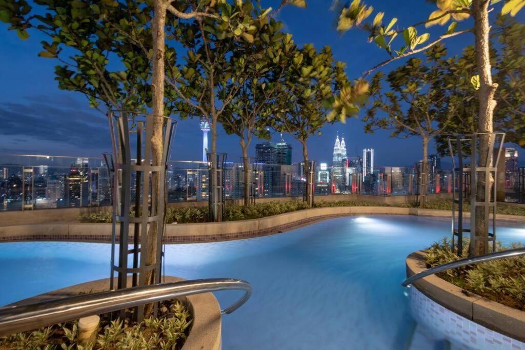 een zwembad met een skyline van de stad op de achtergrond bij The Robertson Bukit Bintang Luxe Suites in Kuala Lumpur