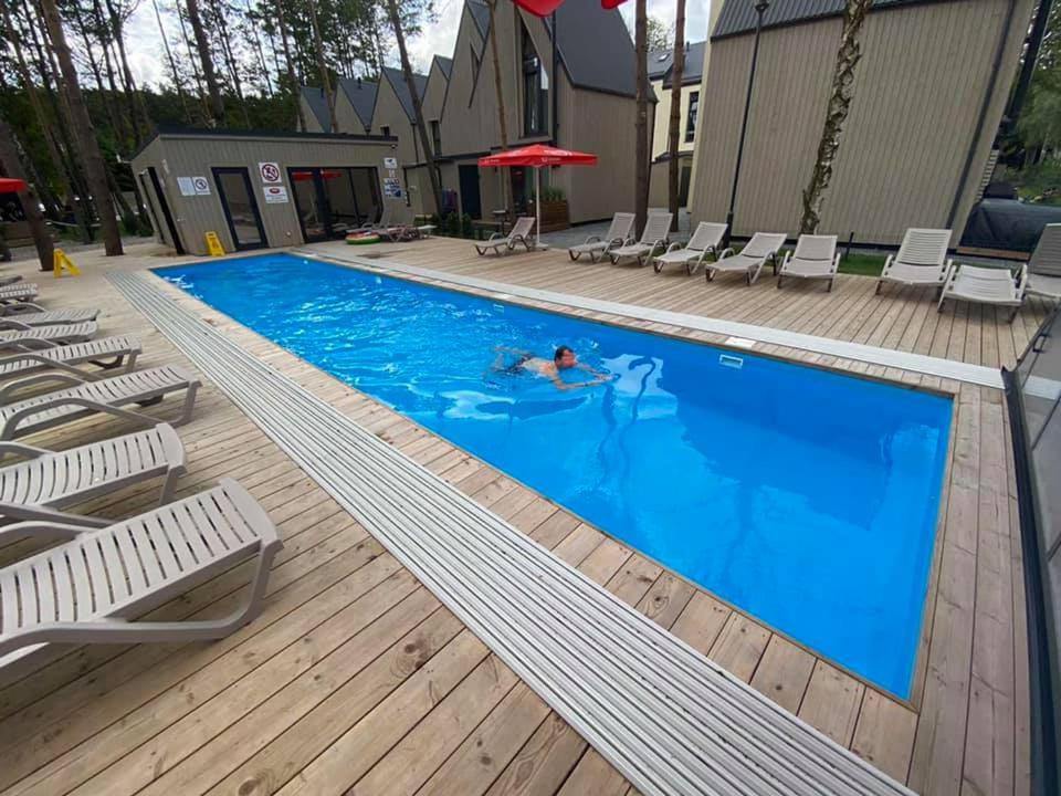 a person swimming in a swimming pool with chairs at Sun&Sea in Palanga