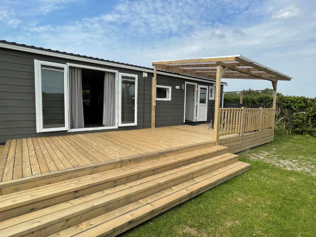 a large wooden deck with a pergola on a house at Polderhuisje 2 - Heerlijk chalet nabij strand en duin - 2 slaapkamers - Midicamping - Rockanje in Rockanje