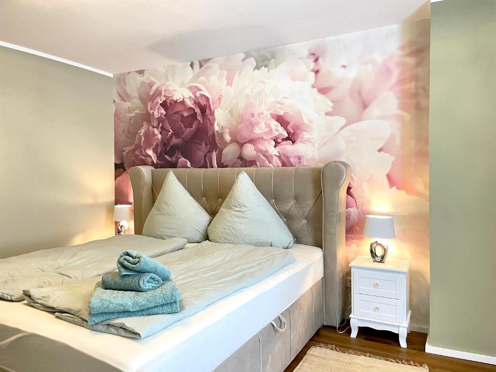 ein Schlafzimmer mit einem Bett mit einem Blumenbild an der Wand in der Unterkunft WEINHOF Winningen Traumwohnung im „La Mosel• in Winningen