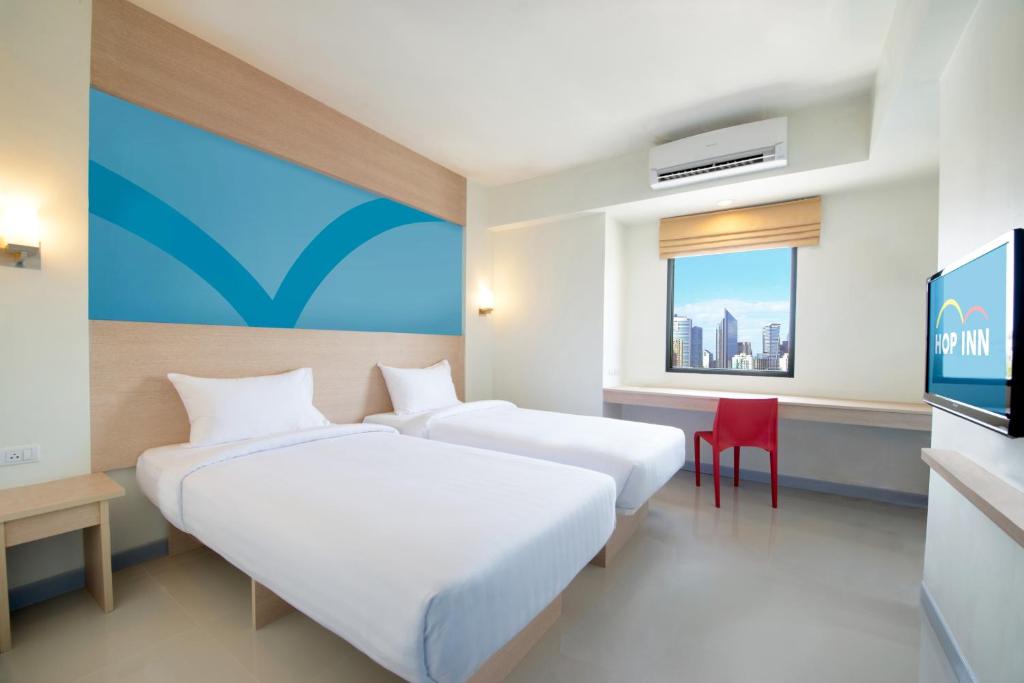 Hop Inn Hotel Cebu City في مدينة سيبو: غرفة فندقية بسريرين وتلفزيون