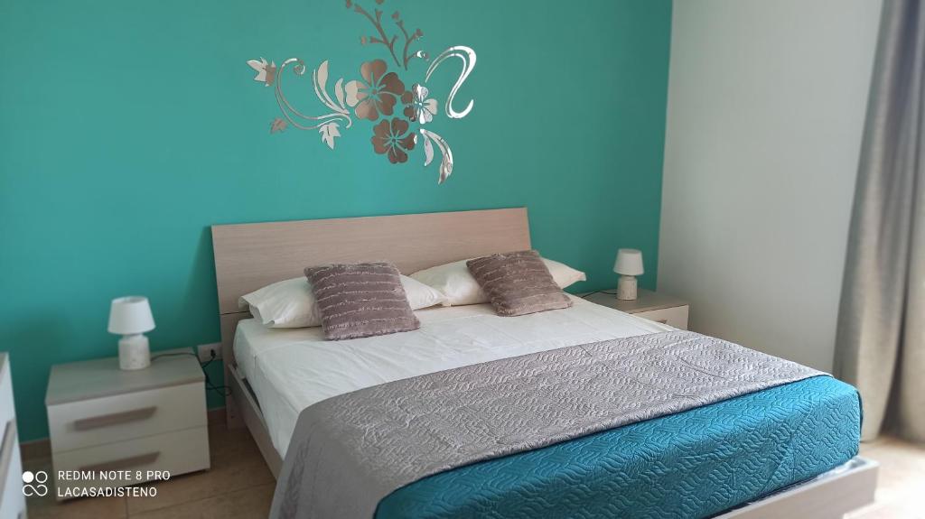 Un dormitorio con una cama con una pared azul. en La casa di Steno, en Lecce