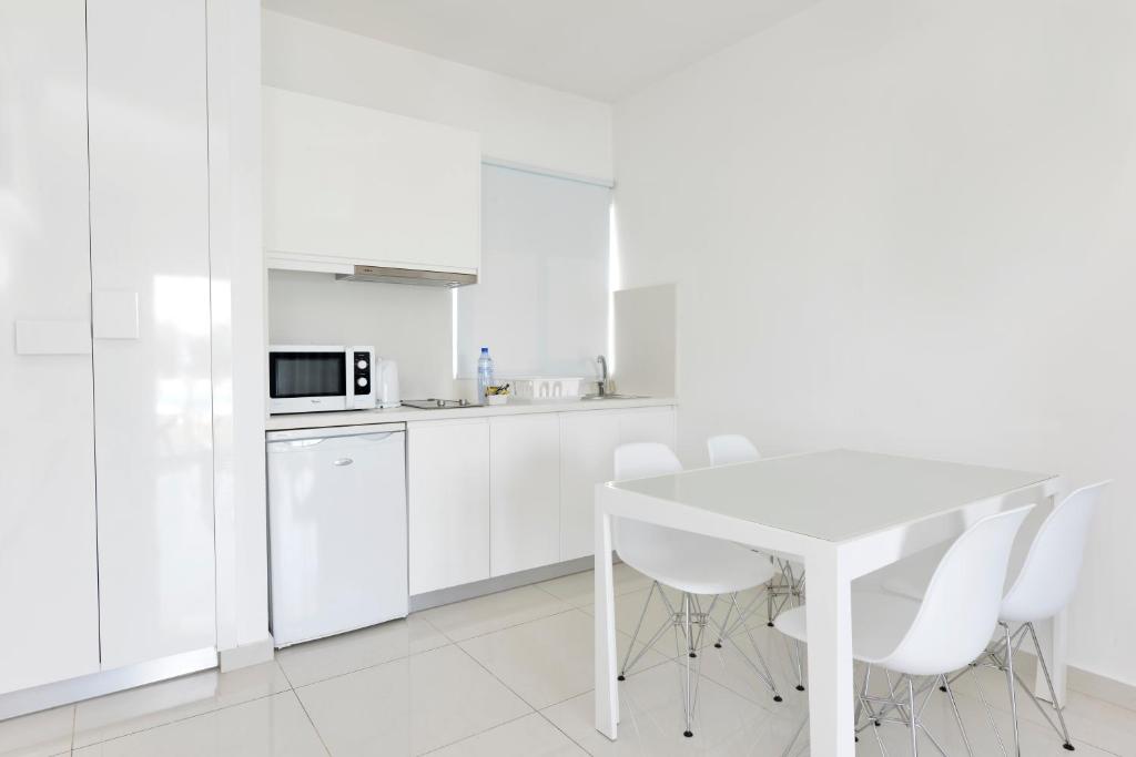a white kitchen with a white table and white appliances at Mon Repos Hotel in Ayia Napa