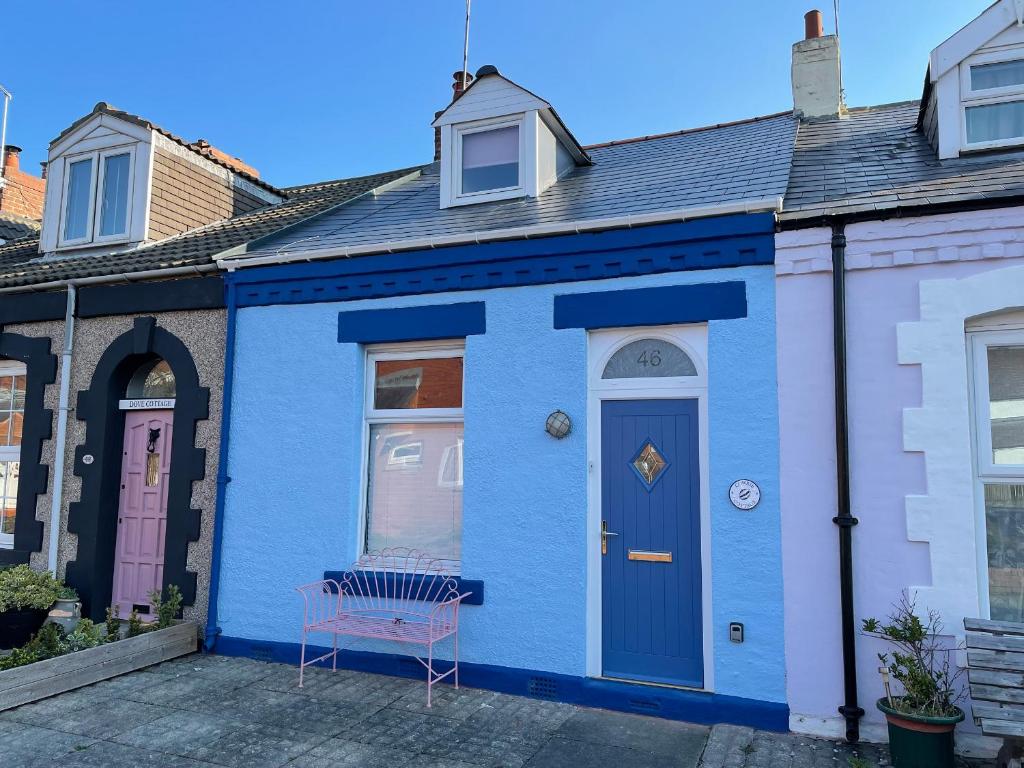 una casa azul con un banco delante en Cowrie Cottage, en North Shields