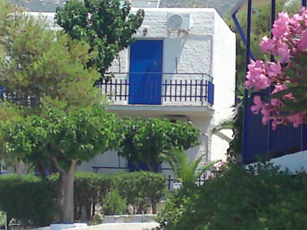 a building with a blue door and a balcony at Aetos Beach Bungalows in Karistos