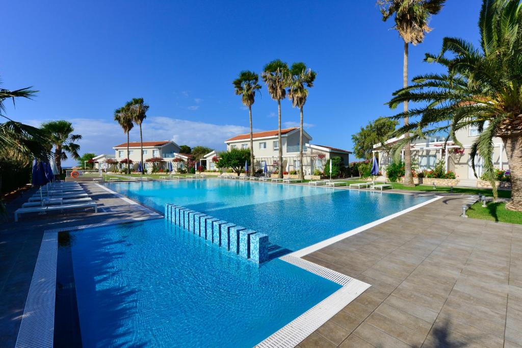 a large swimming pool with palm trees and houses at Mon Repos Hotel in Ayia Napa