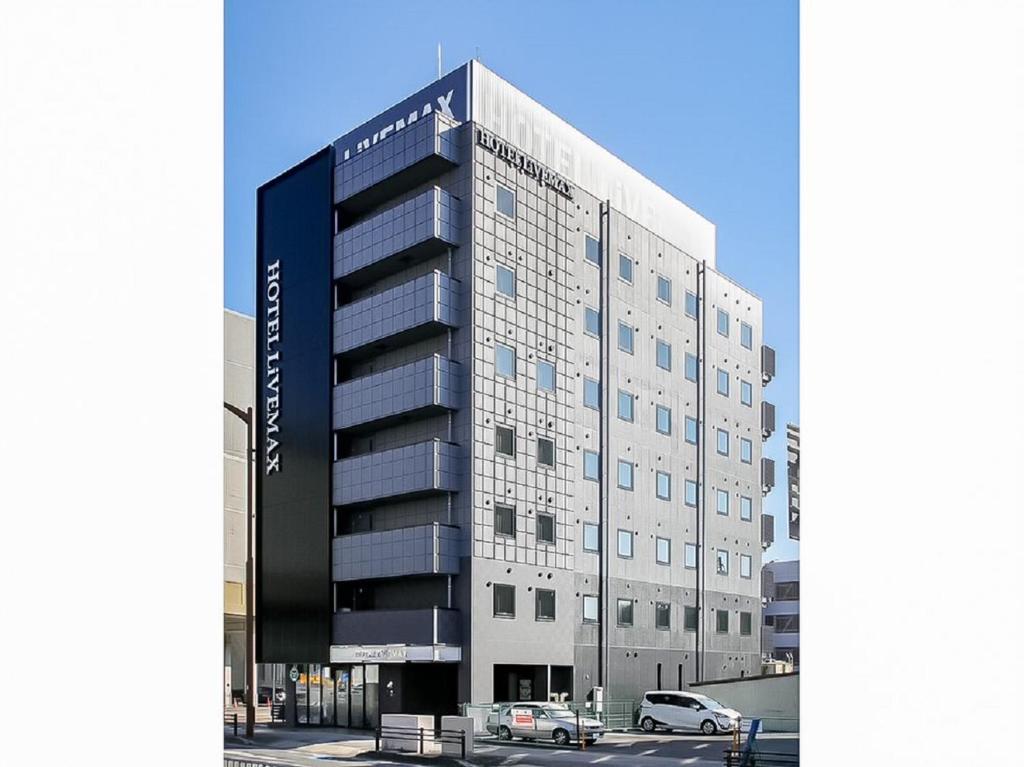 un edificio alto con una macchina parcheggiata di fronte di HOTEL LiVEMAX Aichi Toyota Ekimae a Toyota