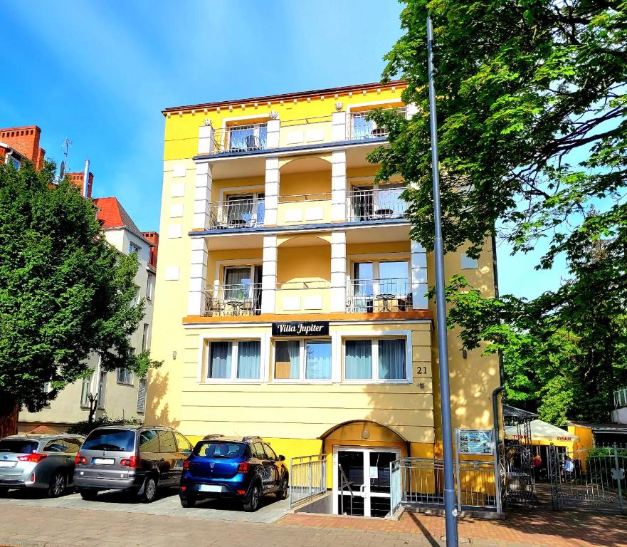 a yellow building with cars parked in front of it at Villa Jupiter in Świnoujście