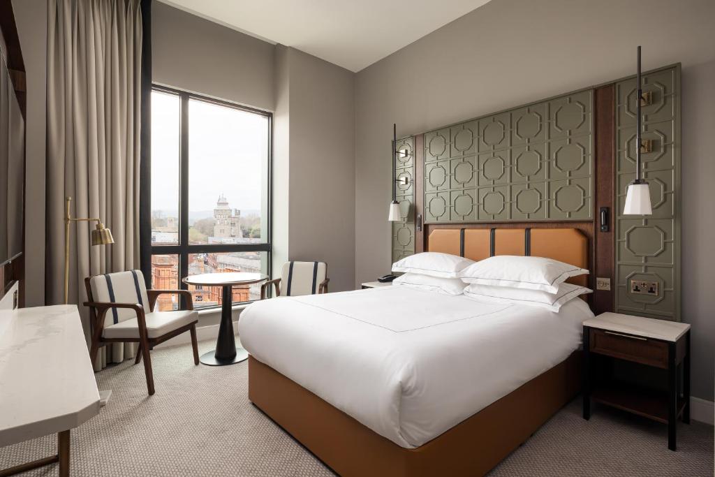 a hotel room with a large bed and a table at The Parkgate Hotel in Cardiff