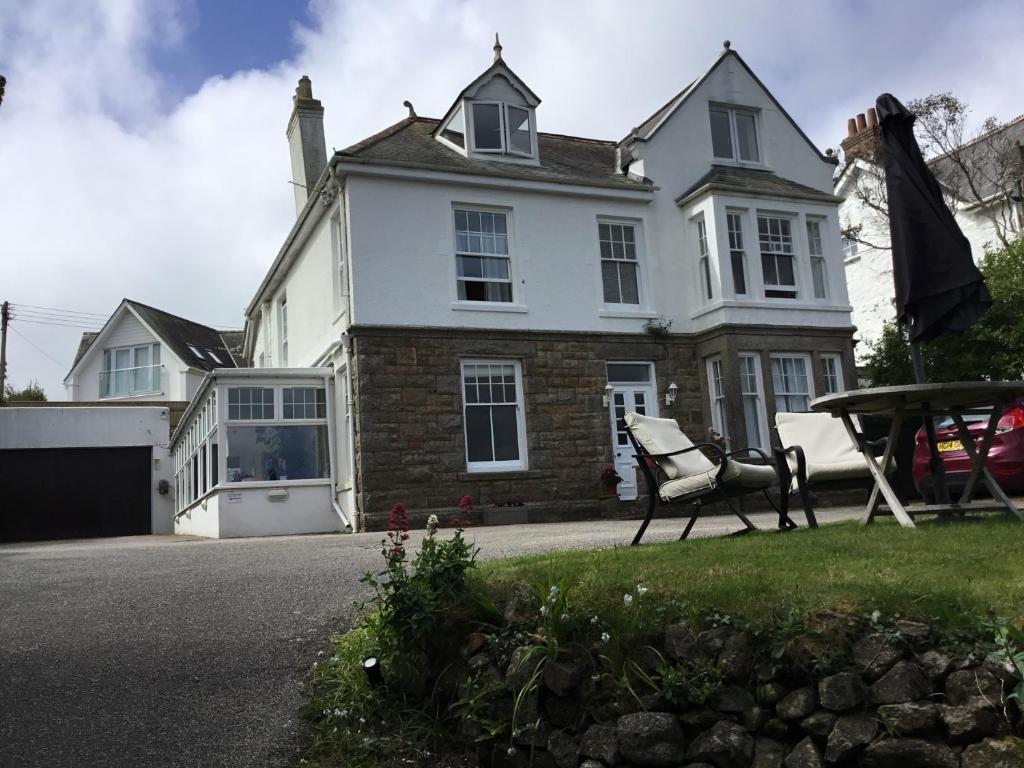 a white house with a table and chairs in front of it at Borthalan House in Carbis Bay