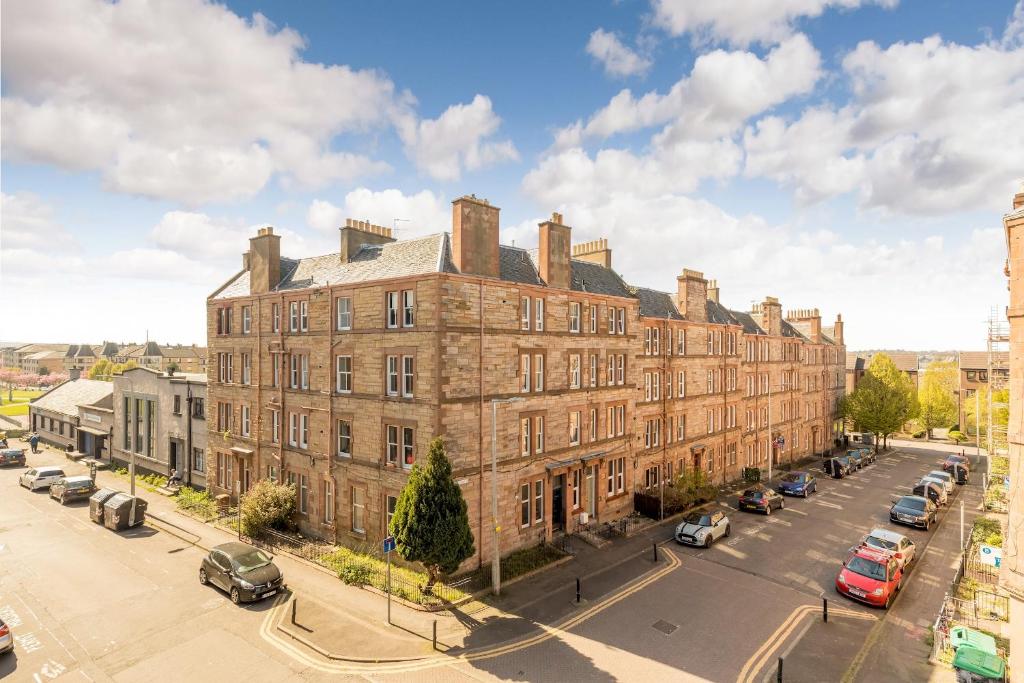 a large brick building with cars parked on a street at Pass the Keys Stunning 3 Bed Loft Style Apt with Free Parking in Edinburgh