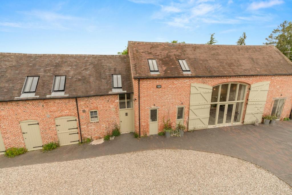 a brick building with two garage doors and a driveway at The Loft at Kington Grange in Claverdon