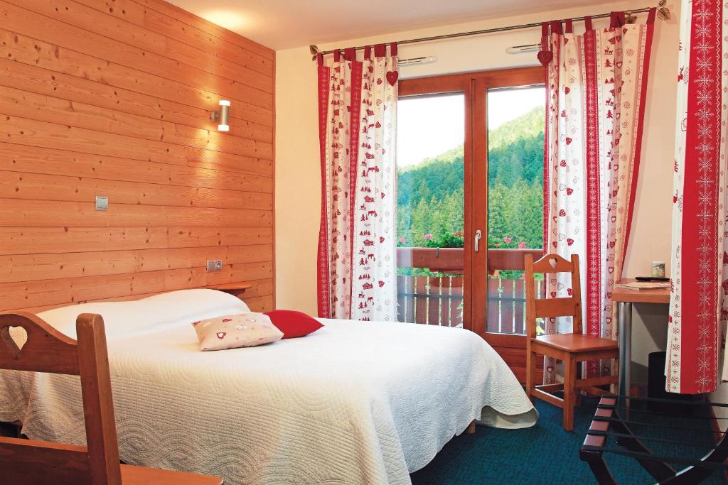 um quarto com uma cama e uma janela em Hôtel Le Vétiné em Le Valtin
