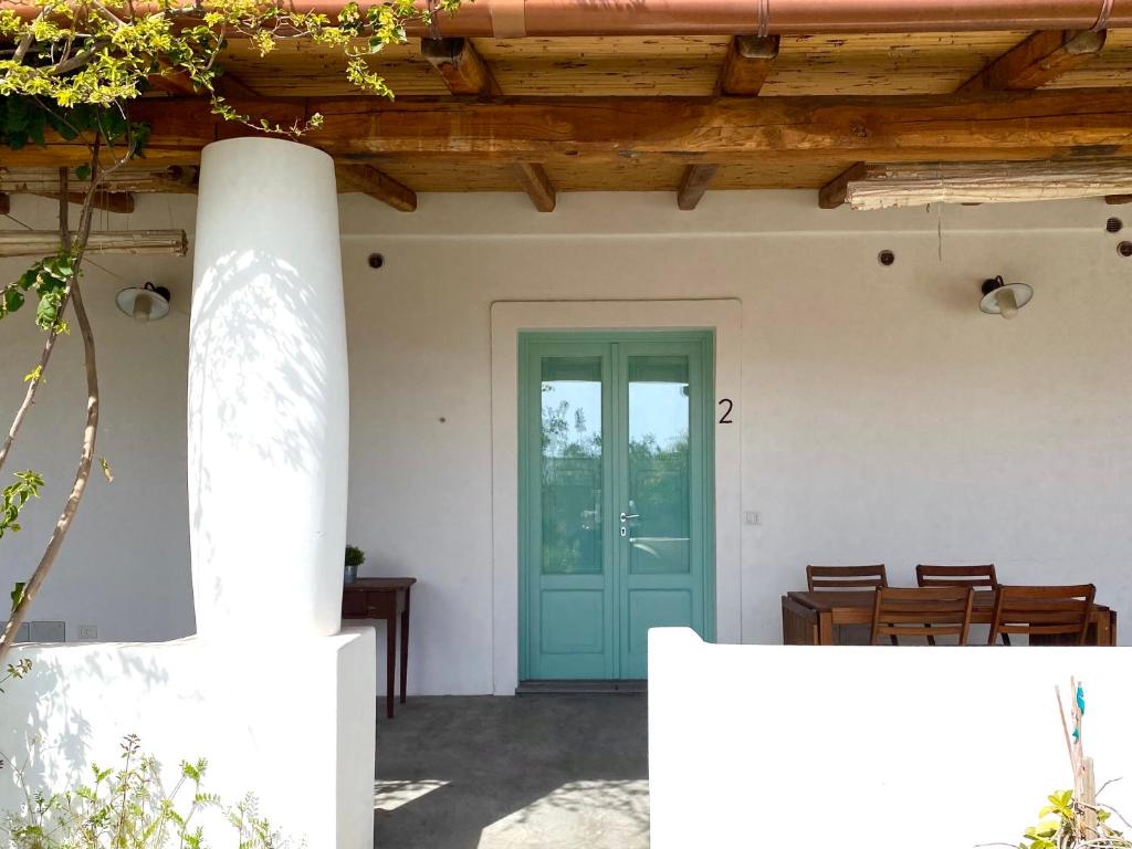 eine blaue Tür in einem weißen Haus mit Holzdecken in der Unterkunft Appartamenti Alba&Tramonto in Stromboli