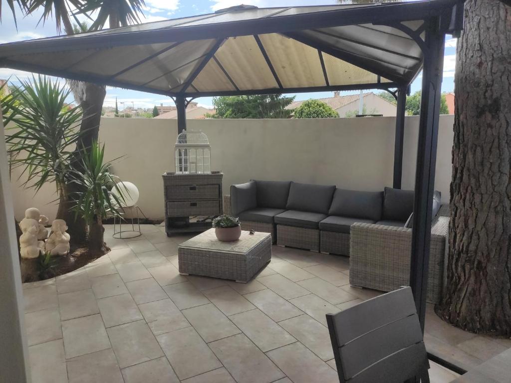 a patio with a couch under an umbrella at Chez Didier et Myriam in Portiragnes