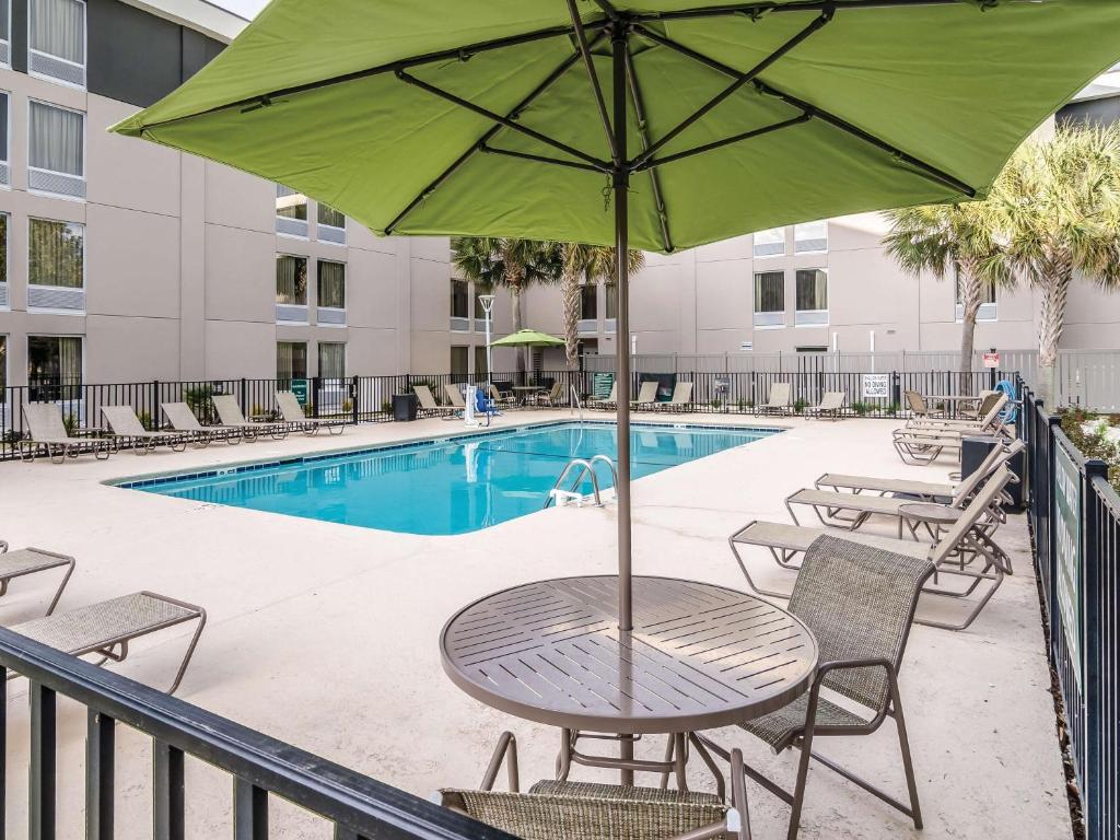 a table with an umbrella next to a pool at La Quinta by Wyndham Myrtle Beach - N. Kings Hwy in Myrtle Beach