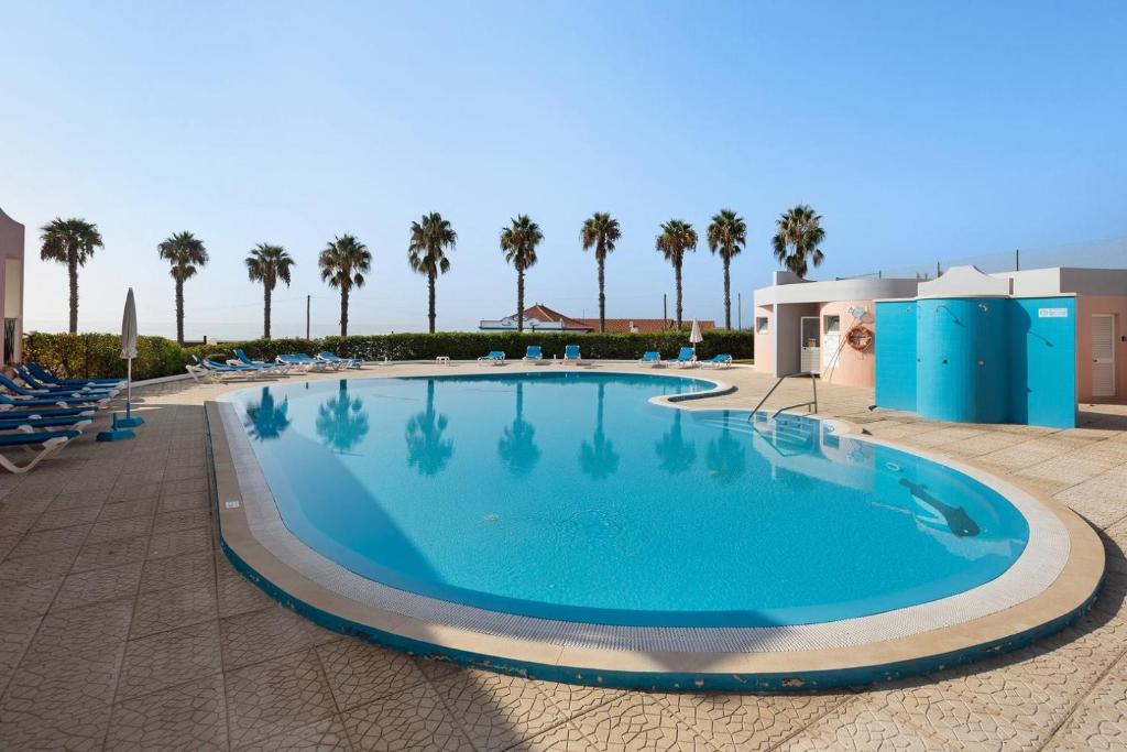 una grande piscina con palme sullo sfondo di Cantinho da Sara a Portimão