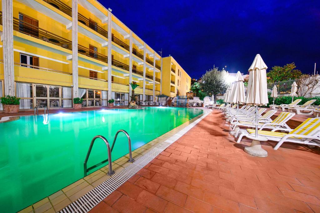 una piscina con sillas y sombrillas junto a un hotel en Grand Hotel Terme di Augusto, en Isquia