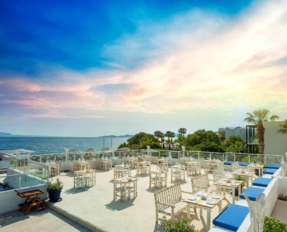 a patio with tables and chairs overlooking the ocean at CHARM BEACH HOTEL in Akyarlar