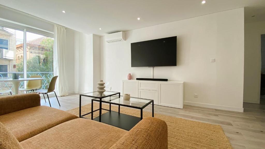 un salon avec un canapé et une télévision sur un mur dans l'établissement Vilmorin Appartement 1 Chambre proche de gare, plage, centre, à Antibes