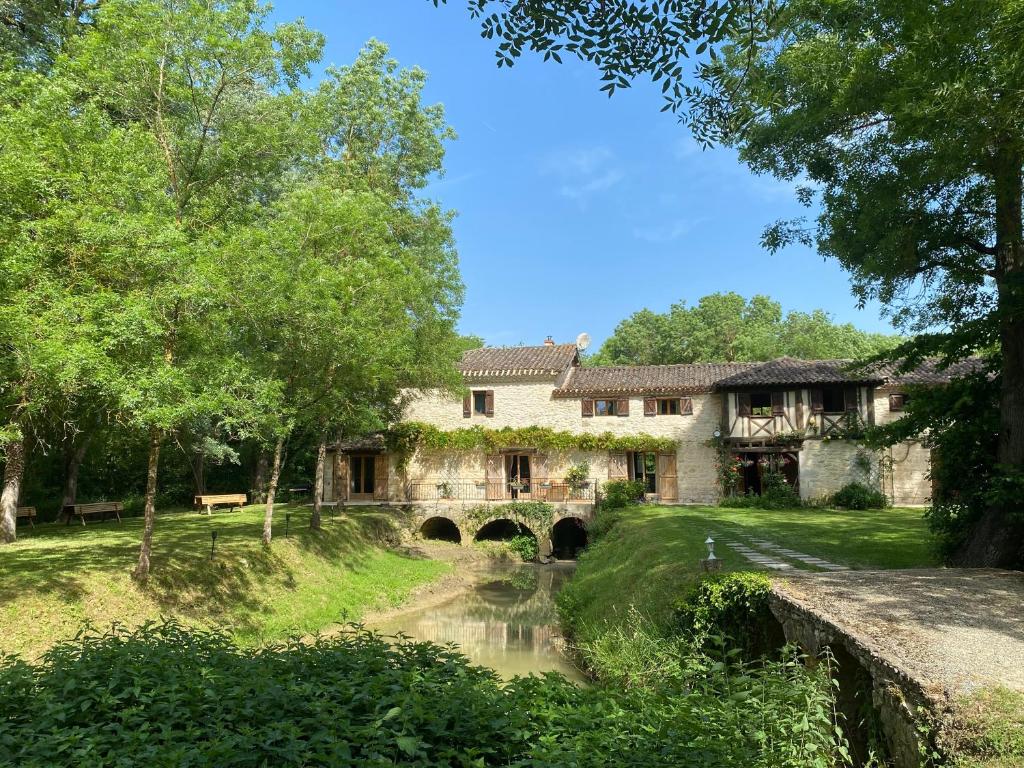 an old stone house with a bridge over a river at Gîte le Moulin Samsara in Homps