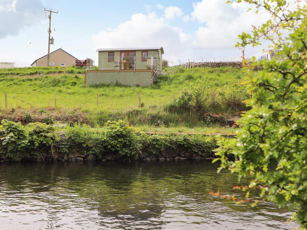 a house on top of a hill next to a river at Llety'r Bugail 1 in Caernarfon