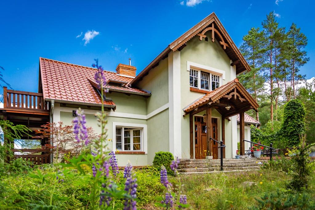 una pequeña casa blanca con techo rojo en Mazurska Leśniczówka Nowy Zyzdrój, en Nowy Zyzdrój