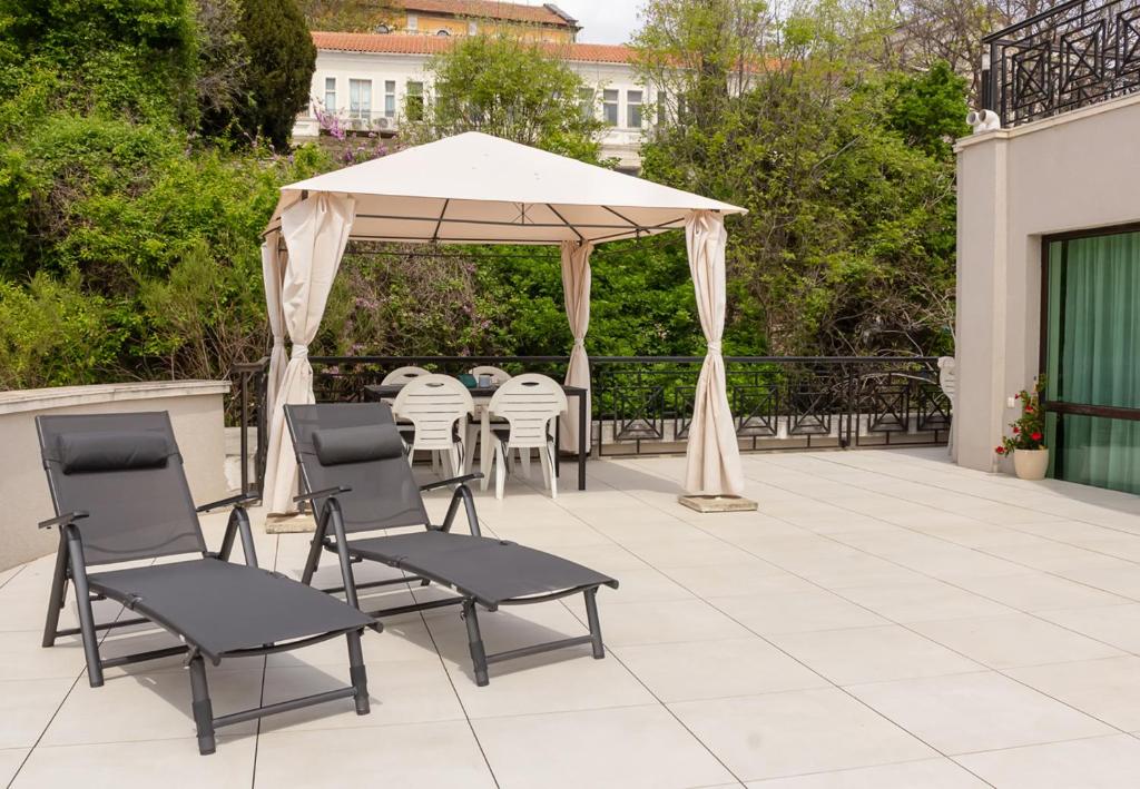 - un kiosque avec des chaises et des tables sur la terrasse dans l'établissement Cozy 1BD Apartment with a Spacious Terrace, à Balchik