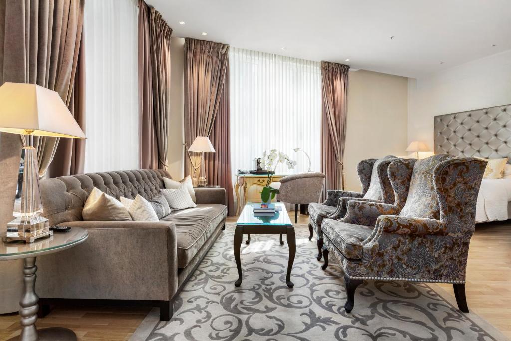 a living room with a couch and chairs and a bed at Hotel Continental in Oslo