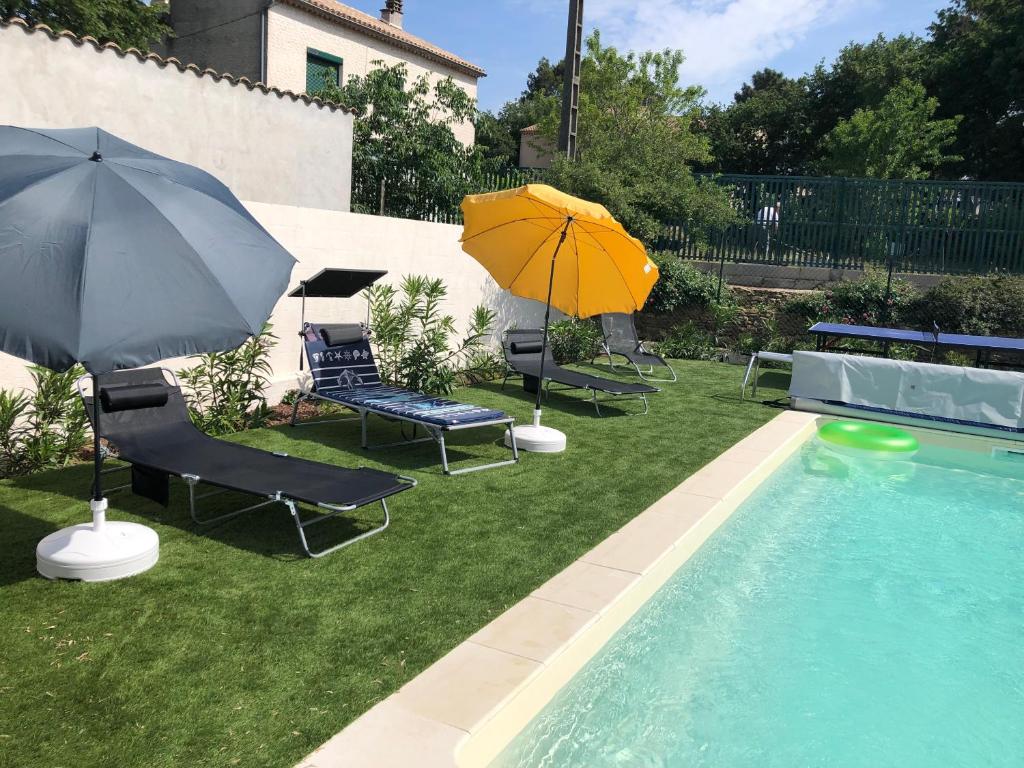 uma piscina com dois guarda-sóis e cadeiras e uma piscina em Gite climatisé avec piscine sur les hauteurs de Bollene em Bollène