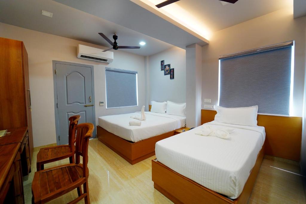 1 dormitorio con 2 camas, silla y escritorio en MOSHIS NEST, en Madurai