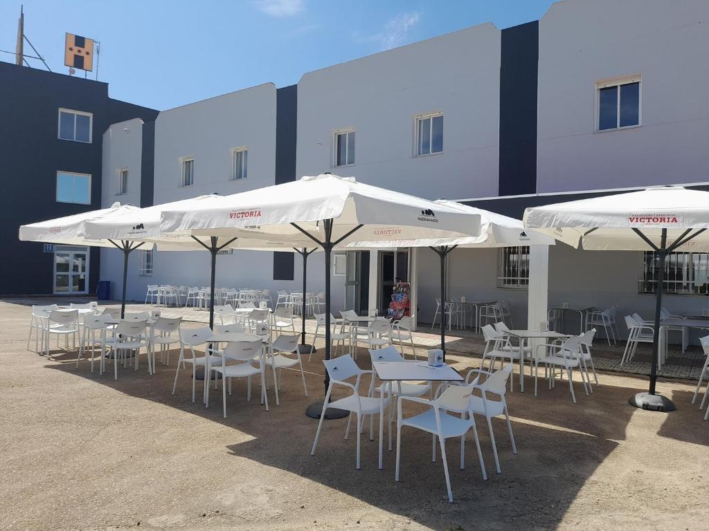 un grupo de mesas y sombrillas frente a un edificio en HOTEL ORIANA en Badajoz