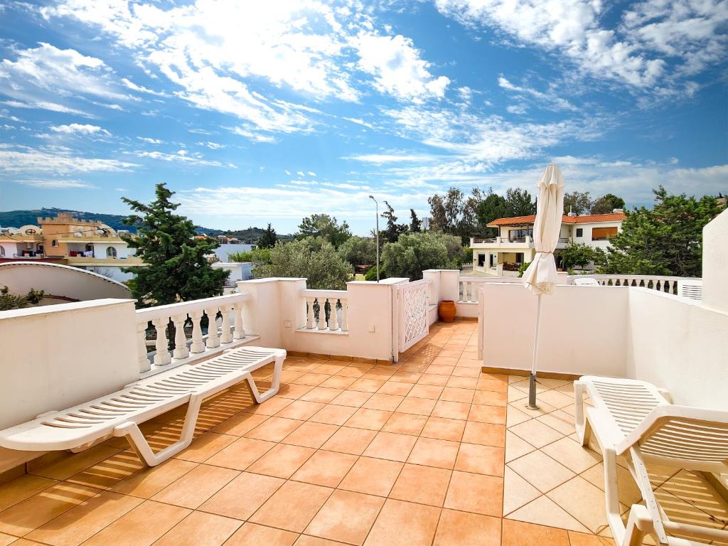 a balcony with white furniture and a blue sky at Colonial Studio/Apartment in Faliraki