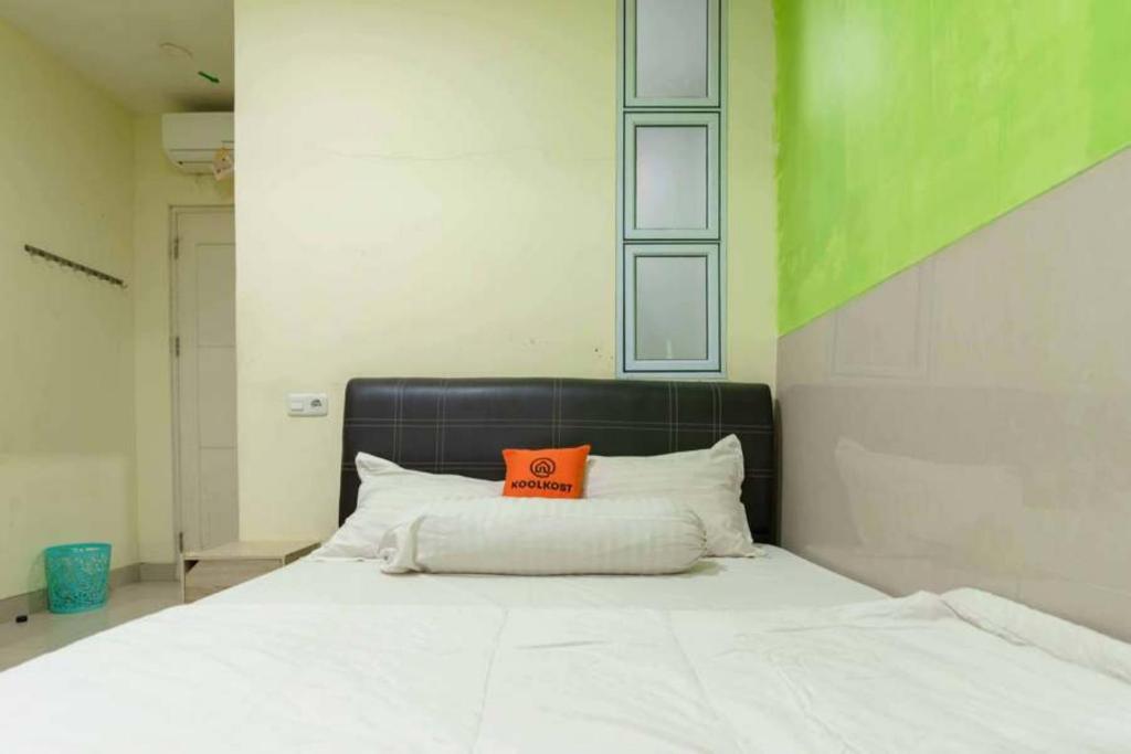 Una cama con una almohada naranja encima. en KoolKost near Nagoya Hill Batam (Minimum Stay 30 Nights) en Nagoya