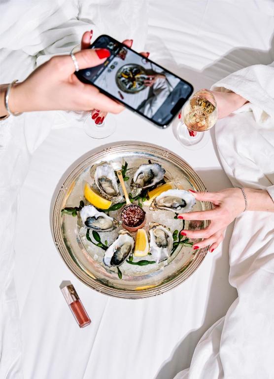 a woman taking a picture of a plate of oysters at Hotel Continental in Oslo