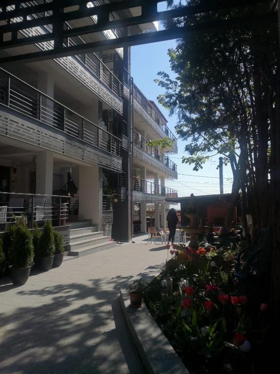 a person walking past a building with flowers in a courtyard at Hotel La John in Vama Veche