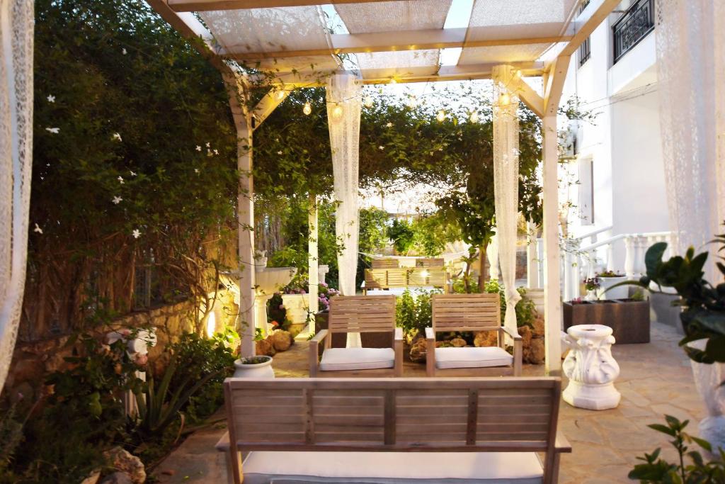 a gazebo with two benches in a garden at Olympus Studios in Malia
