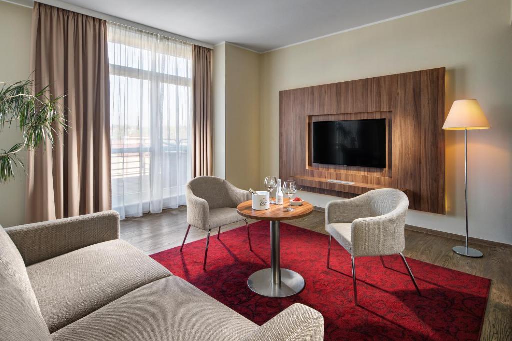 a living room with a table and chairs and a tv at Clarion Hotel Prague Old Town in Prague